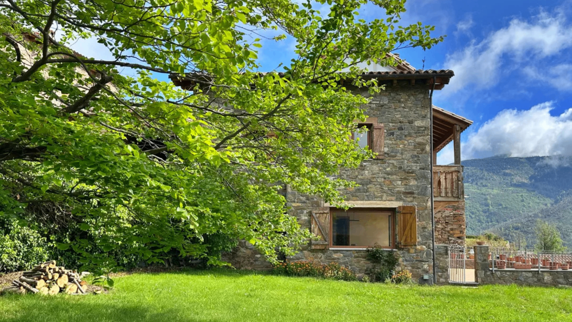 Casa de pedra amb arbres i muntanyes a Catalunya